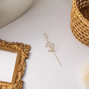 Detailed view of a golden crescent moon ear cuff with sparkling zircon on a white stone background