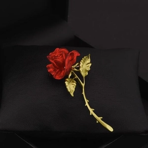 Elegant red rose brooch with gold stem on a black textured display, 1688 jewelry style