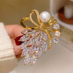 Élégante broche nœud dorée avec cristaux marquise et grande perle blanche à la main