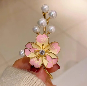 Macro d'une broche fleur de pêcher rose avec pétales émaillés et perles délicates