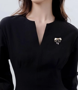 Detail of high-end bow brooch with white pearls pinned on a black V-neck garment