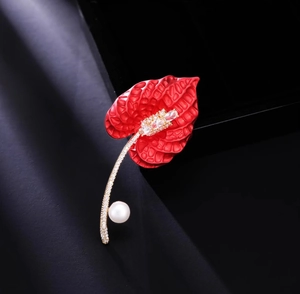 Macro detail of calla lily brooch with red petals, pavé crystals and a white pearl