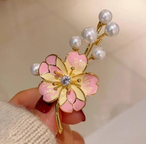 Gros plan d'une broche fleur de pêcher rose avec perles et zircon sur base dorée