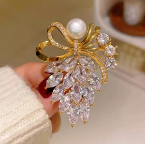 Élégante broche nœud doré avec une grande perle blanche et zircons étincelants