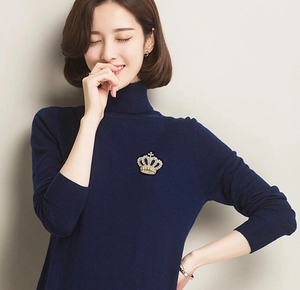 Sparkling gold crown brooch with rhinestones worn on a dark navy blue sweater