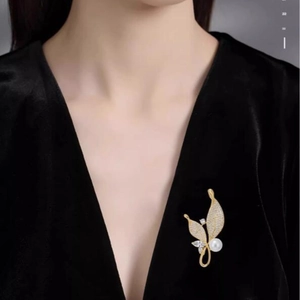 Broche élégante en forme de feuille dorée avec perle et cristaux sur un costume en velours