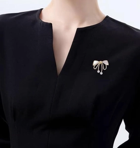 Close-up of elegant bow brooch with white shell wings and hanging pearl droplets