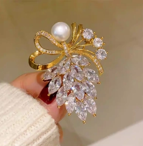 Vue rapprochée d'une broche nœud dorée ornée de cristaux marquise et d'une perle