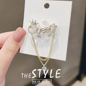 Golden Queen crown brooch with tassels and drop crystals on a white display card