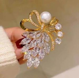 Détail d'une broche nœud doré avec diamants marquise et une grande perle blanche