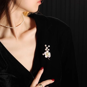 Ensemble broche fleur de pêcher rose et collier de perles sur tenue en velours