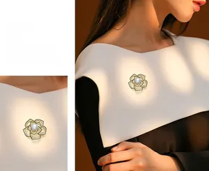 Detailed macro view of a vintage camellia brooch with gold petals and a large center pearl