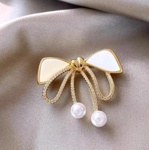 Elegant bow brooch with sparkling crystals and pearl accents on a satin background