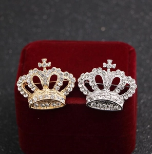 Macro detail of gold and silver crown brooches with cross and white rhinestones