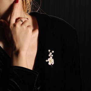 Broche fleur de cerisier en émail rose avec perles sur un blazer en velours noir