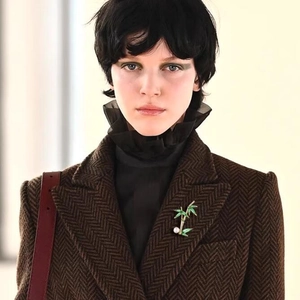 Exquisite bamboo brooch with green enamel leaves and white pearl on a brown wool blazer