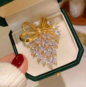 Gros plan détaillé d'une broche dorée avec zircons marquise et perle dans un coffret