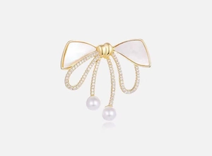 Detailed view of luxury bow brooch with mother-of-pearl inlay and dangling pearls