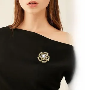 Detailed close-up of a luxury camellia brooch with gold plating and white pearl center