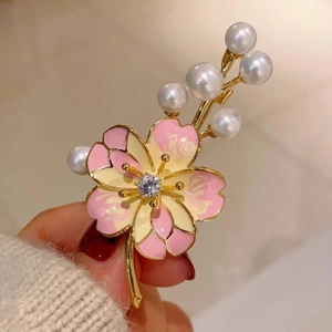 Broche fleur de pêcher rose avec perles et zircon, vue macro tenue à la main