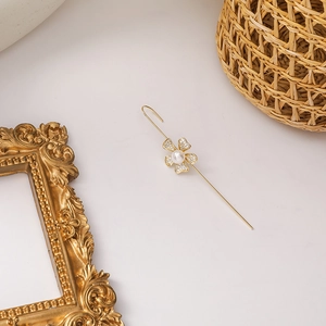 Detailed close-up of golden floral ear cuff with sparkling zircons and a white pearl