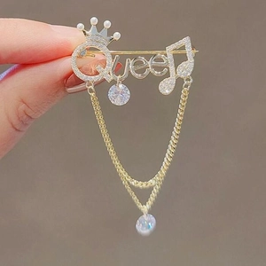 Golden Queen brooch with crown, musical notes, crystal tassels, and pearl accents