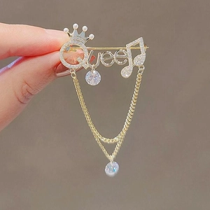Elegant golden Queen brooch with pearl crown and tassel chain shown being held