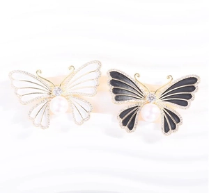 Détails macro des broches papillon émaillées avec zircons et perles centrales blanches