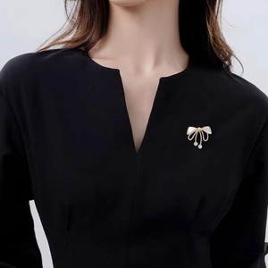 Elegant bow brooch with shell inlay and pearl tassels on black V-neck top