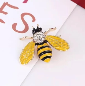 Elegant bee brooch with sparkling crystals and yellow oil dripping wings on a white card