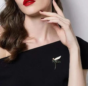 Detail der Libellen-Brosche mit Emaille-Flügeln und einer rosa Perle auf schwarzem Kleid