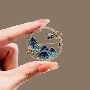 Broche chinoise classique avec paysage vert et nuages dorés dans un cadre doré rond