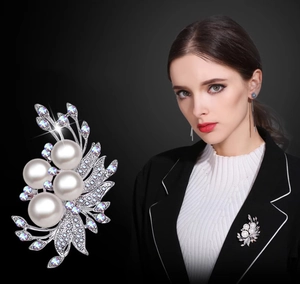 Detail view of pearl floral brooch with silver alloy base and rhinestones on black background