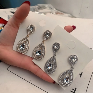 Detail of teardrop dangle earrings in gold and silver with pave-set rhinestones