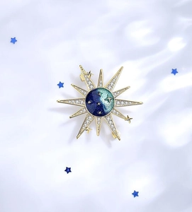 Close-up of golden sunburst brooch with blue gradient enamel and sparkling crystals