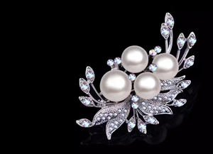 Detailed view of silver flower brooch with white pearls and sparkling AB crystals
