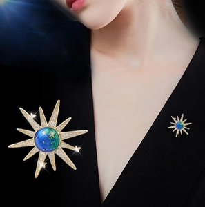 Close-up of golden sunburst brooch with blue starry sphere on a black V-neck garment