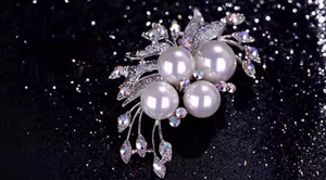 Detailed view of elegant silver floral brooch with large pearls and sparkling rhinestones