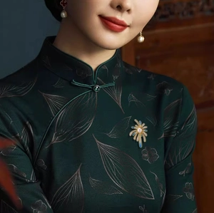 Détail d'une broche fleur en émail bleu avec perle sur une robe chinoise en soie verte