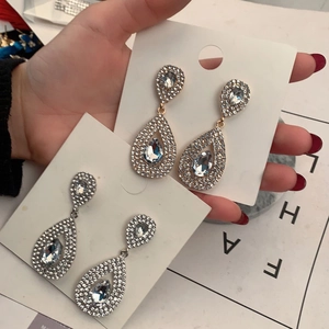 Macro shot of sparkling teardrop earrings in gold and silver finish with full pave diamonds