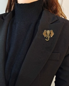 Detail of vintage gold elephant head brooch with amber rhinestones on a black suit jacket