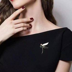 Eleganter Libellen-Anstecker aus Gold mit grünem Emaille und Perle auf Kleid