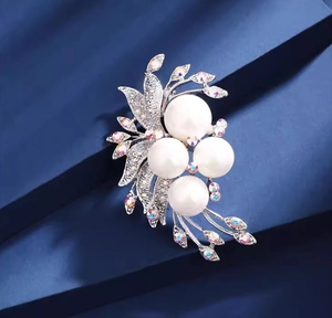Macro detail of silver floral brooch with white pearls and sparkling aurora crystals