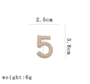 Detailed view of the Number 5 brooch measuring 2.5cm by 3.8cm with pearls and rhinestones