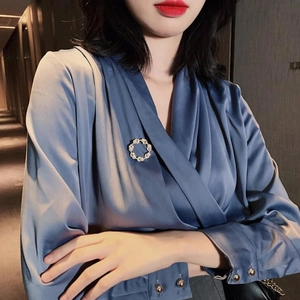 Détail d'une broche ronde en perles sur une chemise en satin bleu pour un style élégant