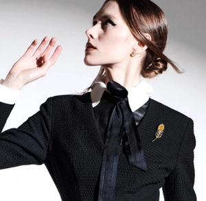 Détail d'une broche plume dorée de luxe avec gemme jaune sur une veste blazer noire