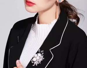 Detail of silver phoenix flower brooch with three pearls and zircons on a black blazer