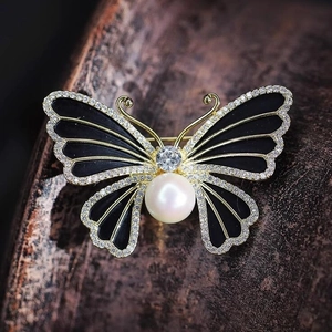 Élégante broche papillon en émail noir avec perle blanche et cristaux scintillants