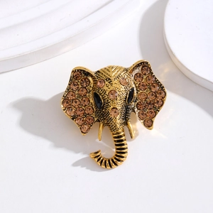 Vintage gold elephant brooch with amber rhinestones on a minimalist white display base
