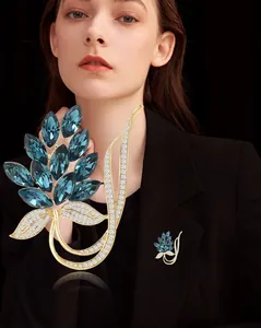 Detail shot of golden floral brooch with deep blue marquise-cut gems and sparkling diamonds